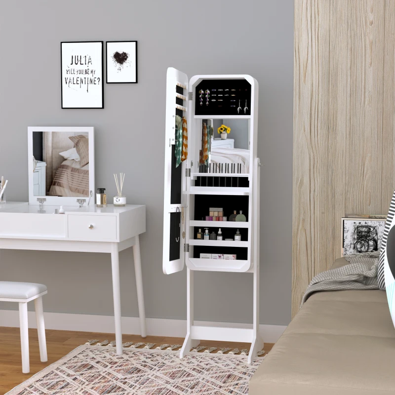 White standing jewelry armoire placed in bedroom corner near vanity desk and bed.