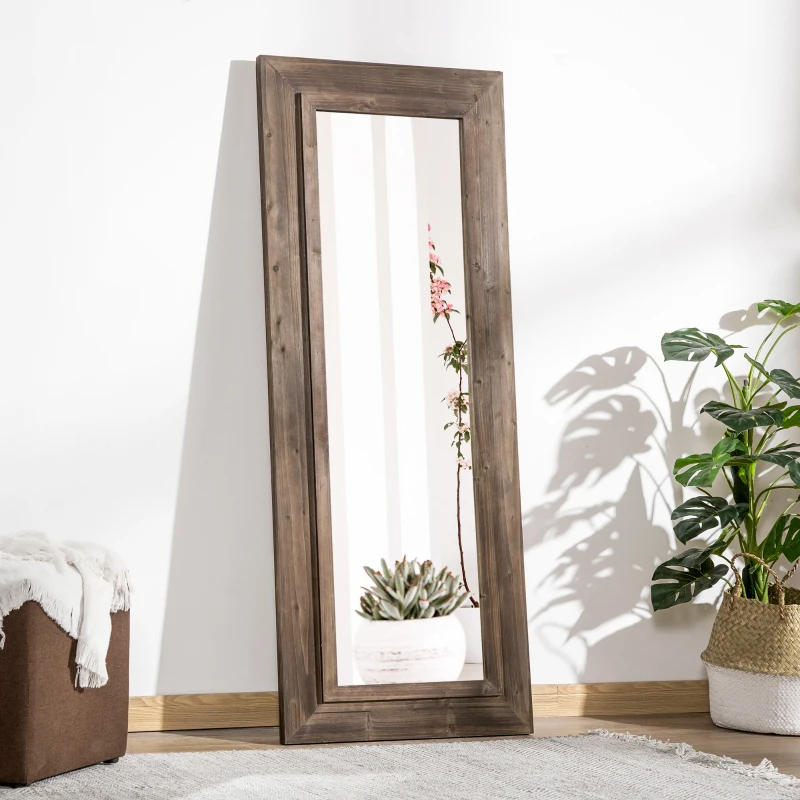 Rustic full-length farmhouse mirror with wooden frame leaning against white wall near plants.