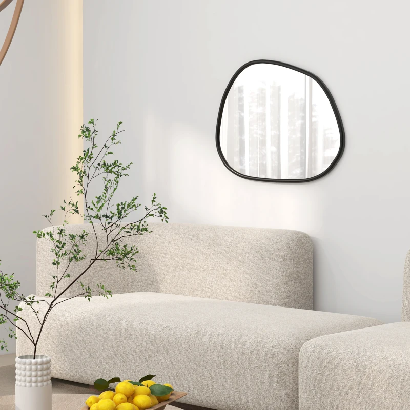 Asymmetrical irregular wall mirror with black frame above modern cream sofa and indoor plant.