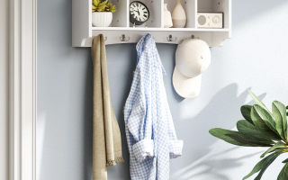 White wall-mounted coat rack with small cubby shelves holding clothes, hat, and decorative items.