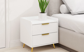 White modern bedside table with gold handles and legs, styled with green potted plant on top.