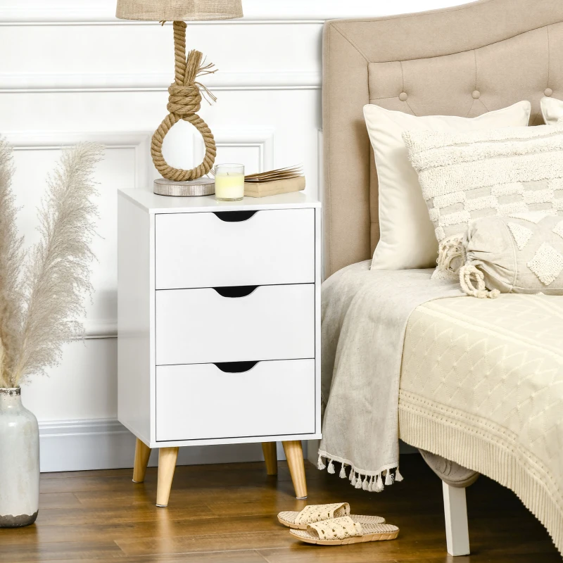 White three-drawer bedside table styled with rope lamp, candle, and cozy neutral bedroom decor.