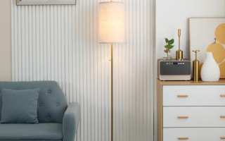 Modern gold floor lamp with fabric shade placed beside sofa and cabinet in a living room.