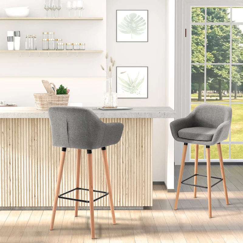 Gray upholstered bar stools with wooden legs near kitchen island