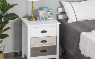 White bedside table with lamp, books, and photo frames in modern bedroom.