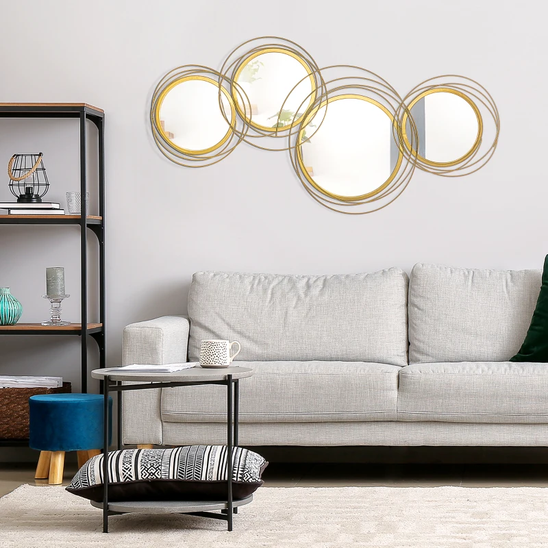 Gold circular metal wall art mirror hanging above gray sofa