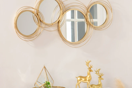 Gold circular metal wall art mirror above console with décor