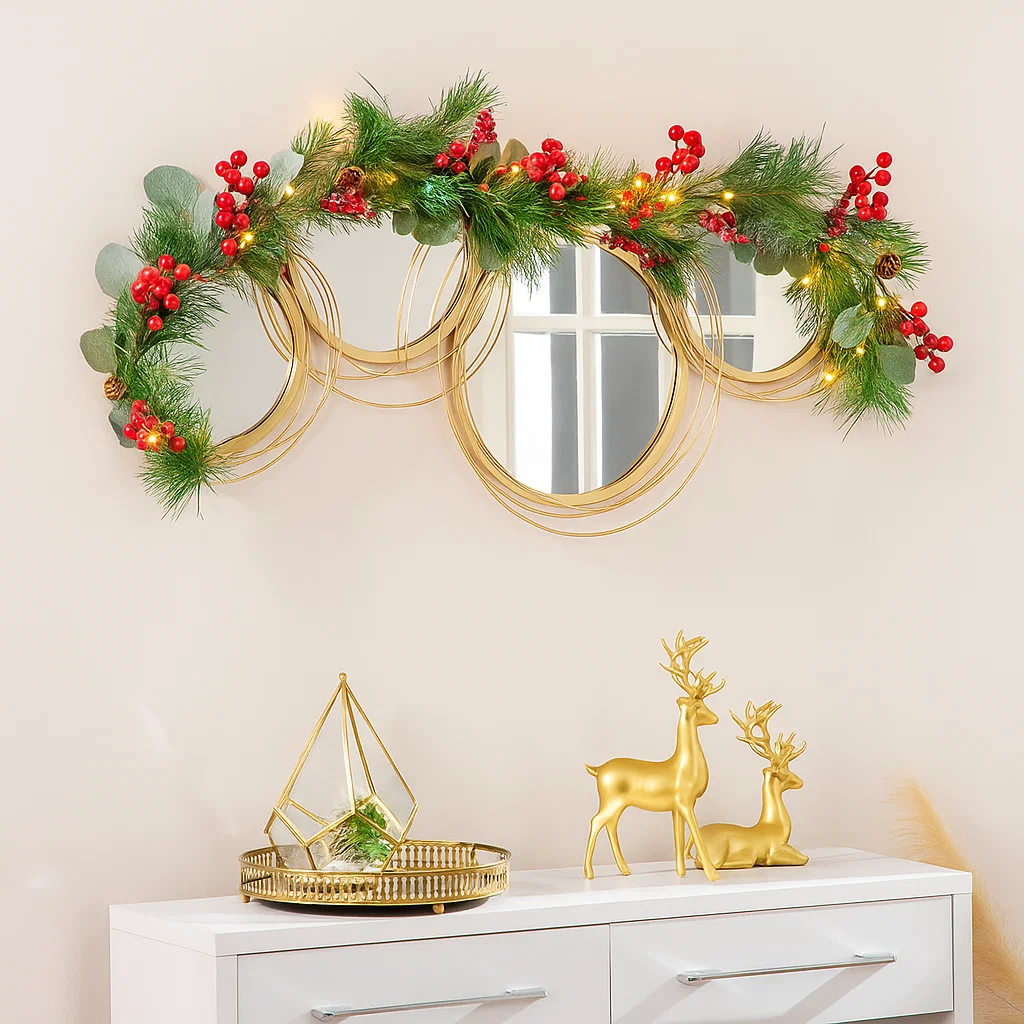 Gold wall art mirror decorated with garland and red berries