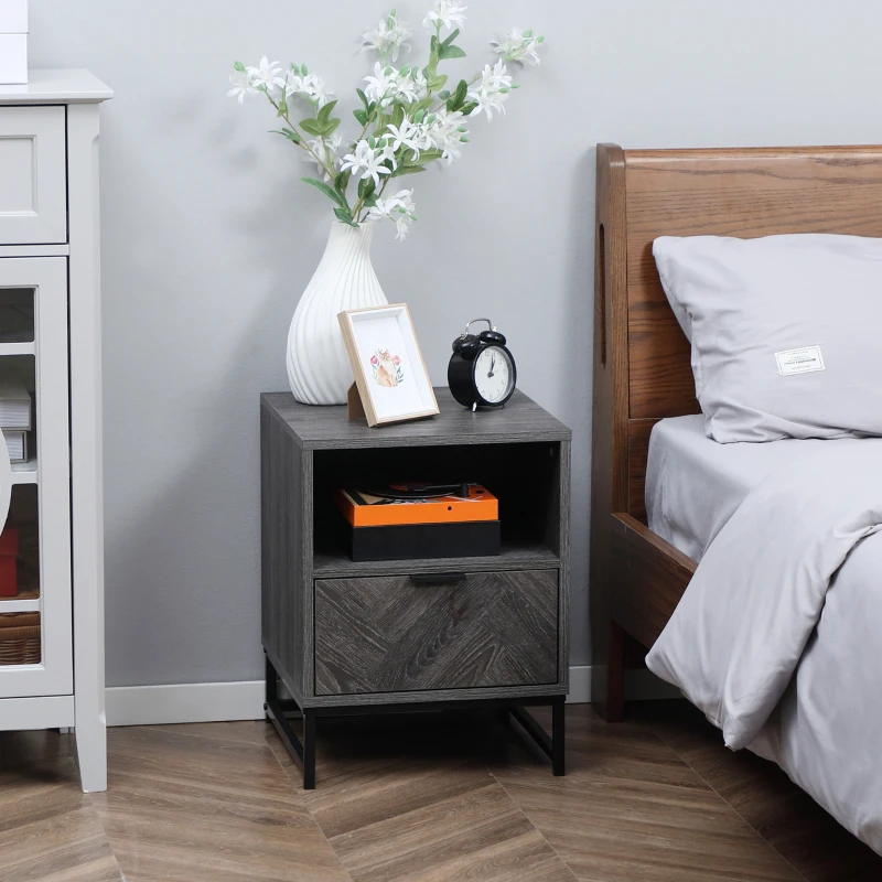 Modern gray bedside table with vase, photo frame, and alarm clock near bed.