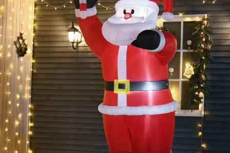 Inflatable Santa Claus holding candy cane outside house with festive lights.