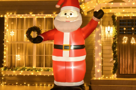 Large inflatable Santa glowing outdoors with festive house lights.