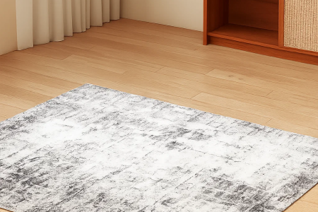 Grey and white area rug laid flat on light wood flooring in a tidy, minimal living room.