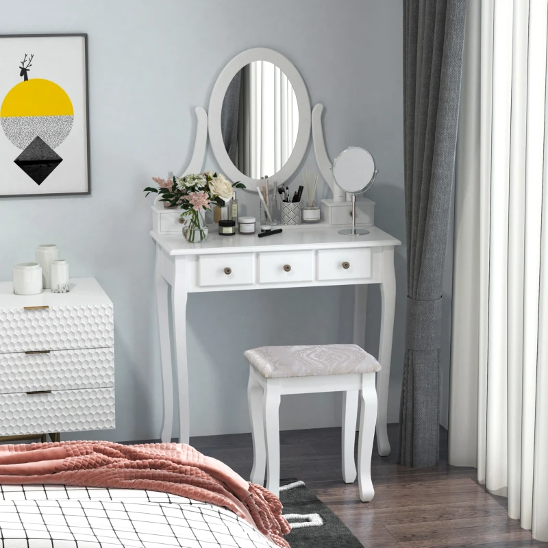 White vanity table with oval mirror decorated with flowers, brushes, and beauty products.