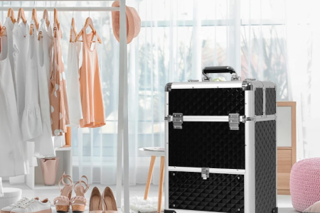Pink rolling makeup train case with open drawers, displaying organized cosmetics in modern living room.