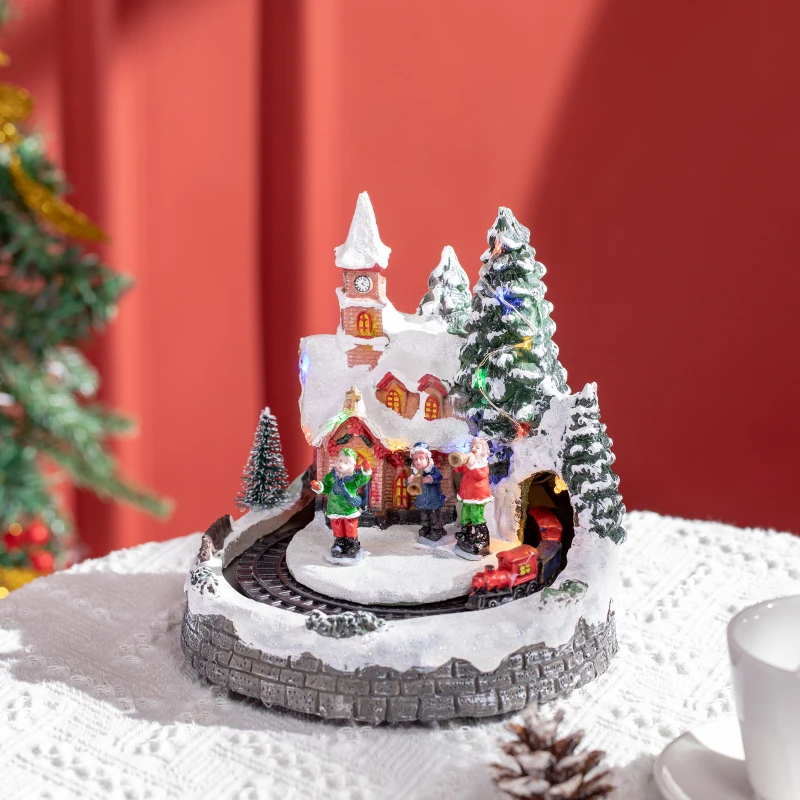 Lighted holiday village scene with snow, church, and small train.