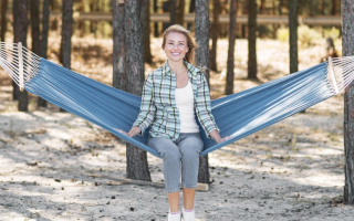 Woman relaxing on blue hammock between trees outdoors