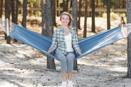 Woman relaxing on blue hammock between trees outdoors