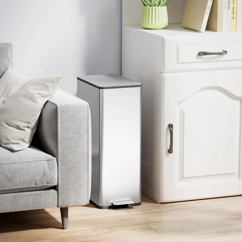Slim tall stainless steel garbage can beside cabinet and sofa.