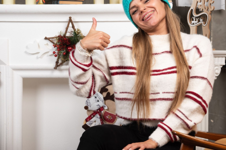 Woman in striped sweater smiling near decorated Christmas mantel.
