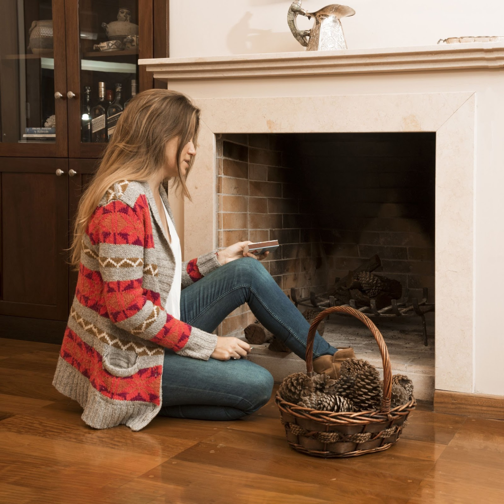 Woman with pinecones basket preparing fireplace for Christmas décor.