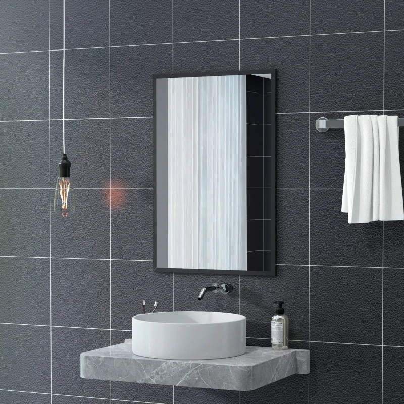 Rectangular mirror on dark tiled bathroom wall above round countertop sink.