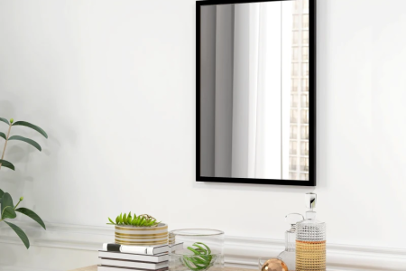 Modern black framed mirror hanging above wooden dresser.