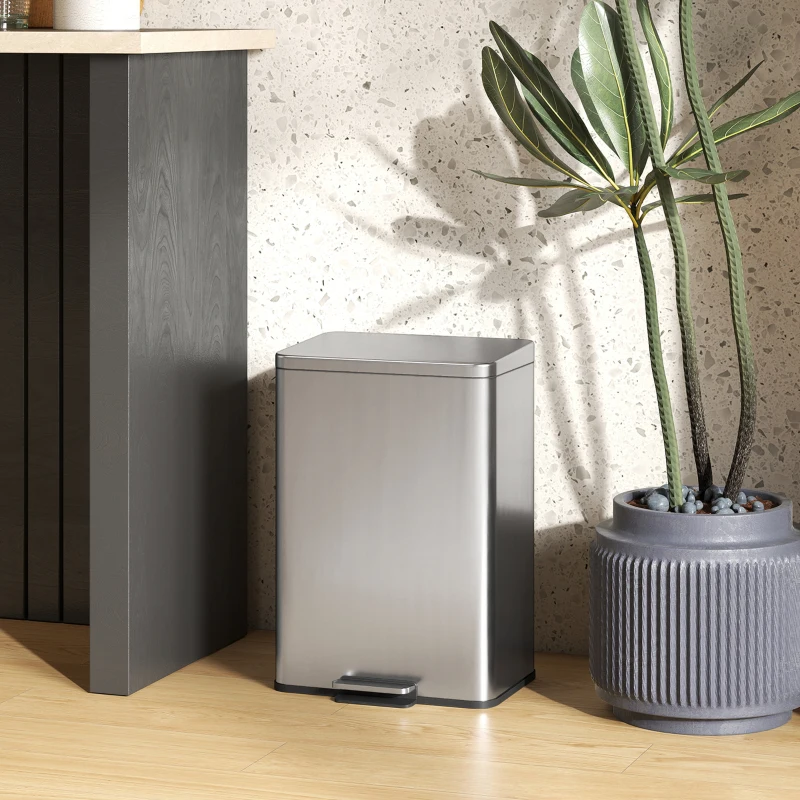 Modern stainless steel trash bin beside indoor plant.