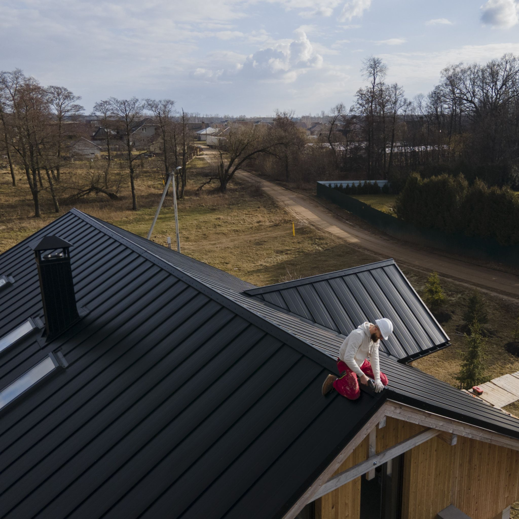 Roofer working on black metal roof of a house