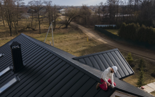 Roofer working on black metal roof of a house