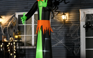 Giant inflatable pumpkin-head figure glowing in decorated yard with spider webs.