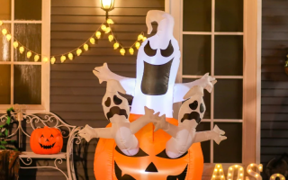 Lighted Halloween inflatable ghost rising from jack-o-lantern outdoors.