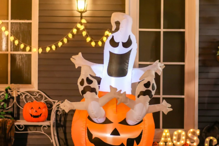 Lighted Halloween inflatable ghost rising from jack-o-lantern outdoors.