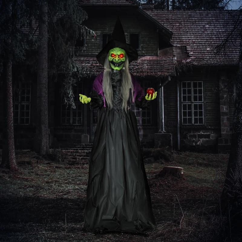 Green-faced witch with glowing red eyes holding poison apple outside haunted house.
