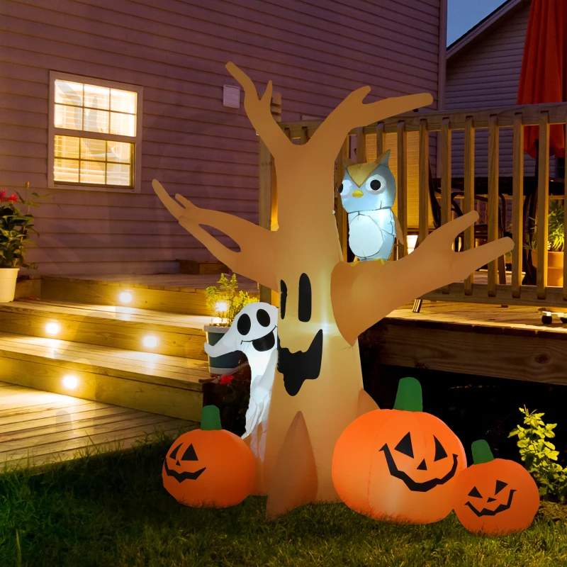 Inflatable haunted tree with pumpkins, owl, and ghost glowing in yard.
