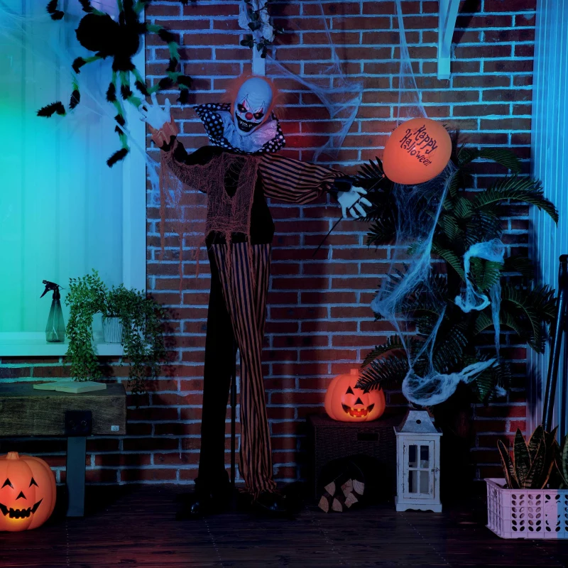 Scary clown with glowing eyes standing by cobwebs and pumpkins outdoors.