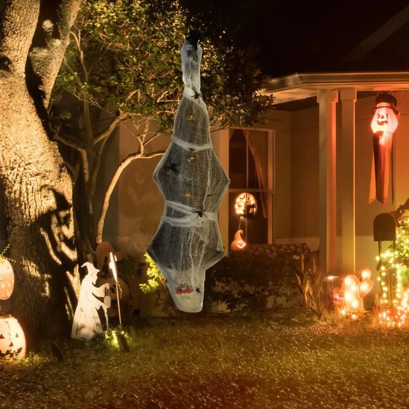 Wrapped mummy hanging upside down in cobwebs with glowing red eyes in yard display.