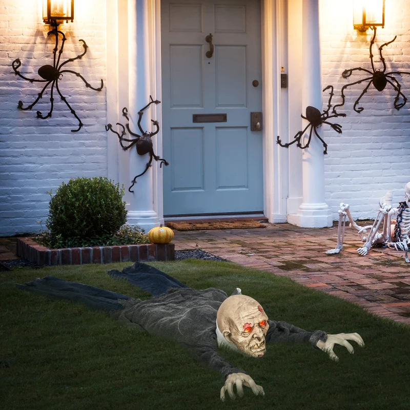 Red-eyed zombie prop crawling across lawn in front of decorated doorway with spiders.