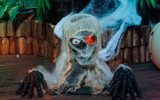Creepy mummy bust with glowing red eye and cobwebs.