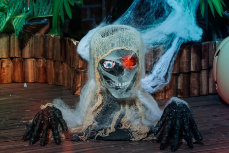 Creepy mummy bust with glowing red eye and cobwebs.