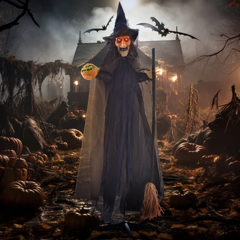 Tall witch decoration with glowing eyes and broom in eerie pumpkin yard.
