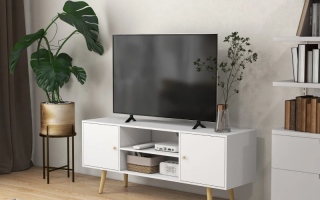 Modern living room with white TV stand, flat screen, and plant.