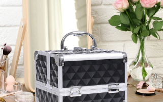 Black diamond-textured makeup train case on vanity beside mirror, flowers, and brushes.