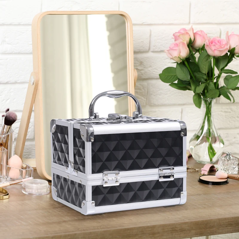 Black diamond-textured makeup train case on vanity beside mirror, flowers, and brushes.