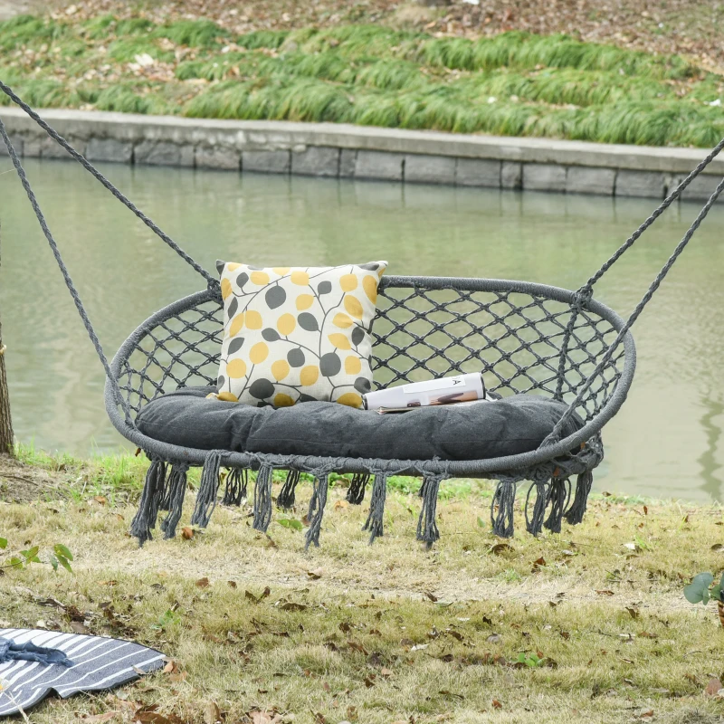 Cozy black hammock chair swing with cushion and decorative pillow by riverside.