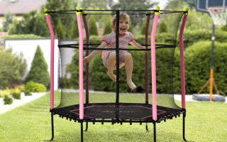 Child jumping on outdoor trampoline with safety net in sunny yard