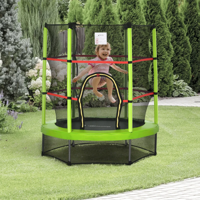 Smiling child jumping on small green trampoline with safety net