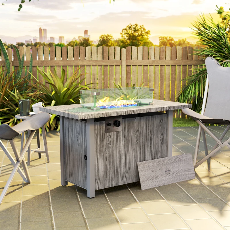 Grey propane fire pit with glass wind guard on patio