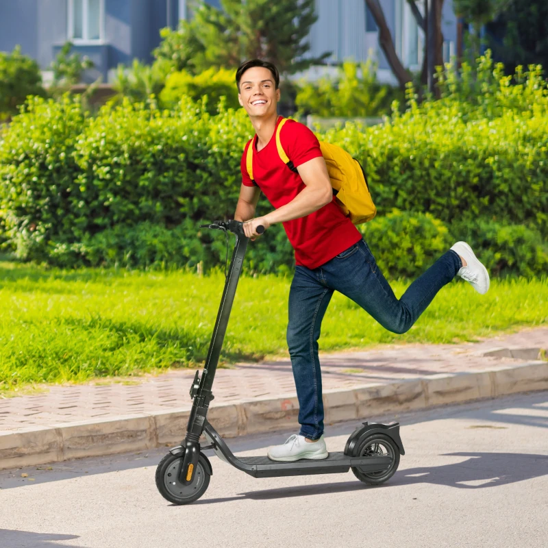 Smiling young man riding black electric scooter on sunny city street.