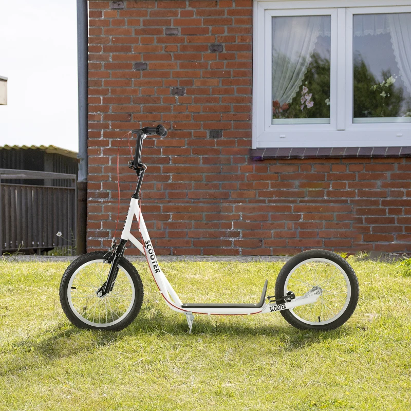White kick scooter parked on green grass beside brick wall house.
