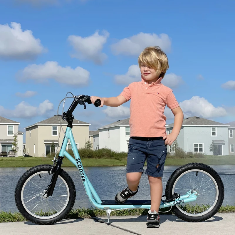 Smiling girl standing on light blue scooter in front yard.